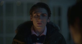 Movie still from “Orphan: First Kill” (2022), directed by William Brent Bell – A young man in a black jacket is looking at the camera; Close Up shot, Over the shoulder angle