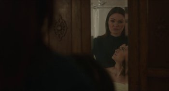 Movie still from “Orphan: First Kill” (2022), directed by William Brent Bell – A woman looking in a mirror while another woman looks on; Close Up shot, Over the shoulder angle