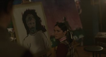 Movie still from “Orphan: First Kill” (2022), directed by William Brent Bell – A woman standing in front of a painting of a man; Medium shot, Over the shoulder angle