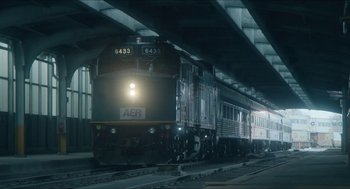 Movie still from “Orphan: First Kill” (2022), directed by William Brent Bell – A train on a train track under a bridge at night time; Extreme Wide shot, Low angle