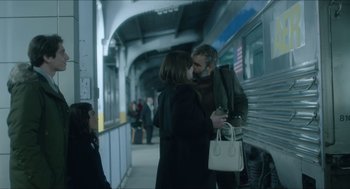 Movie still from “Orphan: First Kill” (2022), directed by William Brent Bell – A man and a woman kissing in front of a train; Medium shot, Over the shoulder angle