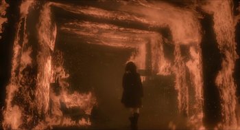 Movie still from “Orphan: First Kill” (2022), directed by William Brent Bell – A person standing in front of a wall of fire; Wide shot, Low angle