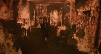 Movie still from “Orphan: First Kill” (2022), directed by William Brent Bell – Two people are sitting in a living room on fire; Wide shot, High angle