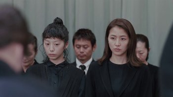 Movie still from “Our Little Sister” (2015), directed by Kore-eda Hirokazu – A group of people in black suits and ties standing next to each other; Medium shot, Low angle