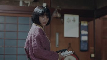 Movie still from “Our Little Sister” (2015), directed by Kore-eda Hirokazu – A woman in a purple robe holding a book in her hands; Medium shot, Over the shoulder angle