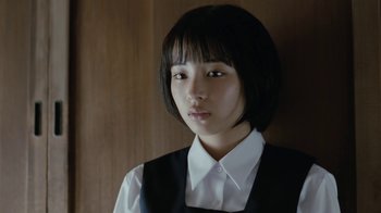 Movie still from “Our Little Sister” (2015), directed by Kore-eda Hirokazu – A young woman with short black hair wearing a white shirt and black vest; Close Up shot, Low angle
