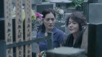 Movie still from “Our Little Sister” (2015), directed by Kore-eda Hirokazu – Two women sitting in front of a grave with flowers; Close Up shot, Over the shoulder angle