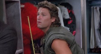 Movie still from “Overboard” (1987), directed by Garry Marshall – A person wearing a vest and holding a stick; Close Up shot, Low angle