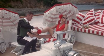 Movie still from “Overboard” (1987), directed by Garry Marshall – A man and a woman sitting on a chair under an umbrella; Wide shot, Low angle