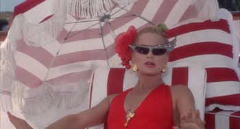 Movie still from “Overboard” (1987), directed by Garry Marshall – A woman in a red dress and sunglasses holding an open umbrella; Close Up shot, Low angle