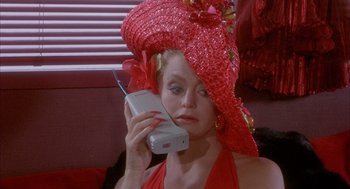 Movie still from “Overboard” (1987), directed by Garry Marshall – A woman wearing a red hat talking on a cell phone; Close Up shot, High angle