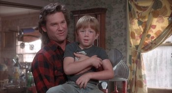 Movie still from “Overboard” (1987), directed by Garry Marshall – A man and a boy are sitting in a room together; Medium shot, Over the shoulder angle