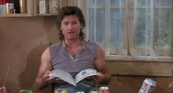 Movie still from “Overboard” (1987), directed by Garry Marshall – A man sitting at a table reading a book; Medium shot, Low angle