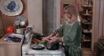 Movie still from “Overboard” (1987), directed by Garry Marshall – A woman in a green checkered dress cooking carrots on the stove; Medium shot, High angle