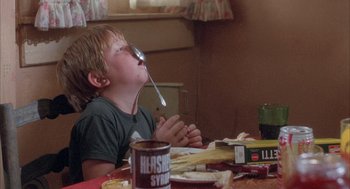 Movie still from “Overboard” (1987), directed by Garry Marshall – A young boy is eating at a table; Medium shot, Low angle