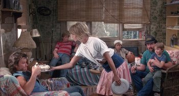 Movie still from “Overboard” (1987), directed by Garry Marshall – A woman holding a frisbee in a room with other people; Wide shot, Over the shoulder angle