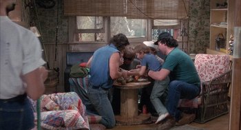 Movie still from “Overboard” (1987), directed by Garry Marshall – A group of people sitting around a wooden table; Wide shot, High angle