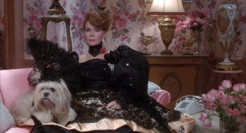 Movie still from “Overboard” (1987), directed by Garry Marshall – A woman in a black dress sitting on a bed; Medium shot, High angle