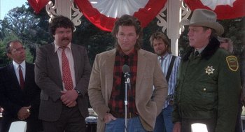 Movie still from “Overboard” (1987), directed by Garry Marshall – A group of men standing next to each other in front of a microphone; Medium shot, Low angle