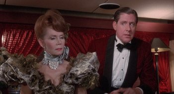 Movie still from “Overboard” (1987), directed by Garry Marshall – An older man and a woman sitting next to each other on a couch; Medium shot, Over the shoulder angle