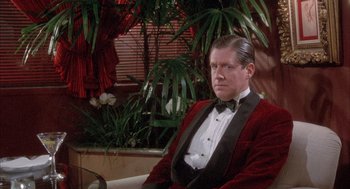 Movie still from “Overboard” (1987), directed by Garry Marshall – A man sitting in a chair wearing a red velvet jacket; Medium shot, Low angle