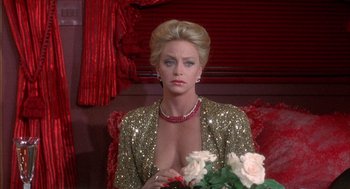 Movie still from “Overboard” (1987), directed by Garry Marshall – A woman sitting on top of a couch with a bouquet of flowers; Close Up shot, Over the shoulder angle