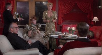 Movie still from “Overboard” (1987), directed by Garry Marshall – Two women sitting on a couch in front of a table; Wide shot, Over the shoulder angle