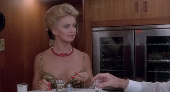 Movie still from “Overboard” (1987), directed by Garry Marshall – A woman sitting at a dinner table with a man; Medium shot, Over the shoulder angle
