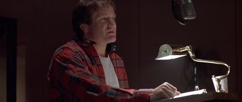 Movie still from “Mrs. Doubtfire” (1993), directed by Chris Columbus – A man wearing a plaid shirt and headphones is playing the piano; Close Up shot, Low angle