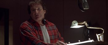 Movie still from “Mrs. Doubtfire” (1993), directed by Chris Columbus – A man wearing a plaid shirt and headphones is sitting in front of a microphone; Close Up shot, Low angle