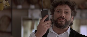 Movie still from “Mrs. Doubtfire” (1993), directed by Chris Columbus – A man holding a cell phone up to his ear; Close Up shot, Low angle