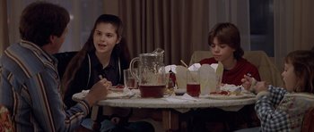 Movie still from “Mrs. Doubtfire” (1993), directed by Chris Columbus – Two children sitting at a dinner table eating food; Medium shot, Over the shoulder angle