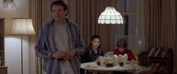 Movie still from “Mrs. Doubtfire” (1993), directed by Chris Columbus – A man standing in front of a table with two people sitting at the table; Medium shot, Over the shoulder angle