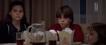 Movie still from “Mrs. Doubtfire” (1993), directed by Chris Columbus – A boy sitting at a table with a box of food in front of him; Close Up shot, Over the shoulder angle