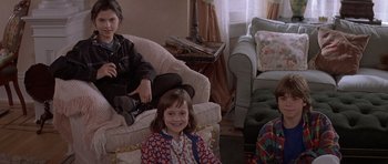 Movie still from “Mrs. Doubtfire” (1993), directed by Chris Columbus – Two children sitting in a living room next to each other; Medium shot, High angle
