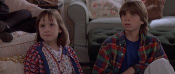 Movie still from “Mrs. Doubtfire” (1993), directed by Chris Columbus – Two people sitting in a living room next to each other; Close Up shot, High angle