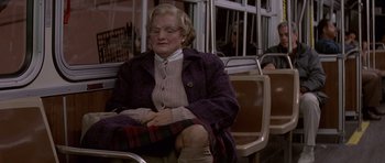 Movie still from “Mrs. Doubtfire” (1993), directed by Chris Columbus – An older woman sitting on a bench in a train; Medium shot, Low angle