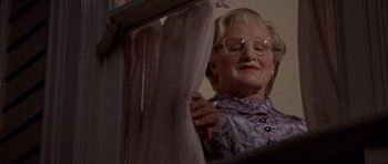 Movie still from “Mrs. Doubtfire” (1993), directed by Chris Columbus – An older woman in glasses looking at a curtain; Medium shot, Low angle
