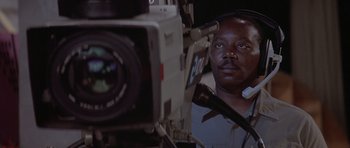 Movie still from “Mrs. Doubtfire” (1993), directed by Chris Columbus – A man with headphones is looking at a camera; Close Up shot, Low angle