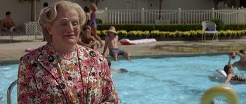 Movie still from “Mrs. Doubtfire” (1993), directed by Chris Columbus – An older woman standing in a pool with a group of people swimming; Medium shot, High angle