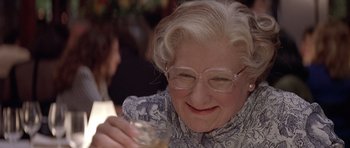 Movie still from “Mrs. Doubtfire” (1993), directed by Chris Columbus – An older woman wearing glasses and holding a glass; Close Up shot, High angle