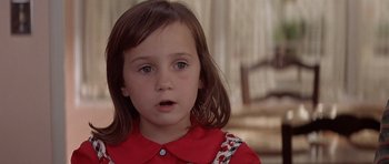 Movie still from “Mrs. Doubtfire” (1993), directed by Chris Columbus – A little girl in a red dress looking at the camera; Close Up shot, High angle