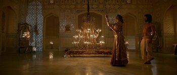 Movie still from “Padmaavat” (2018), directed by Sanjay Leela Bhansali – A woman standing in front of a chandelier in a room; Wide shot, Low angle