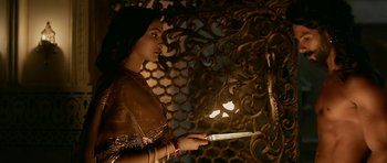 Movie still from “Padmaavat” (2018), directed by Sanjay Leela Bhansali – A woman holding a knife in a room with a wall; Medium shot, Low angle