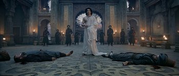 Movie still from “Padmaavat” (2018), directed by Sanjay Leela Bhansali – A group of people in a room with a statue of a man in a white robe; Wide shot, Low angle