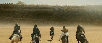 A group of people riding horses on a dirt road