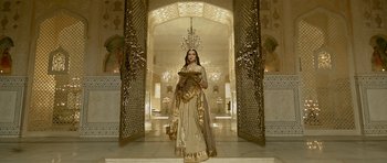 Movie still from “Padmaavat” (2018), directed by Sanjay Leela Bhansali – A woman dressed as a princess standing in front of an archway; Wide shot, Low angle