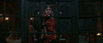 Movie still from “Padmaavat” (2018), directed by Sanjay Leela Bhansali – A woman in a red and orange sari standing in front of a window; Medium shot, Low angle