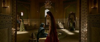 Movie still from “Padmaavat” (2018), directed by Sanjay Leela Bhansali – A woman in a red dress standing next to a man in a red suit; Wide shot, Over the shoulder angle