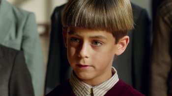 Movie still from “Pain and Glory” (2019), directed by Pedro Almodóvar – A young boy with short hair and a striped shirt; Close Up shot, High angle
